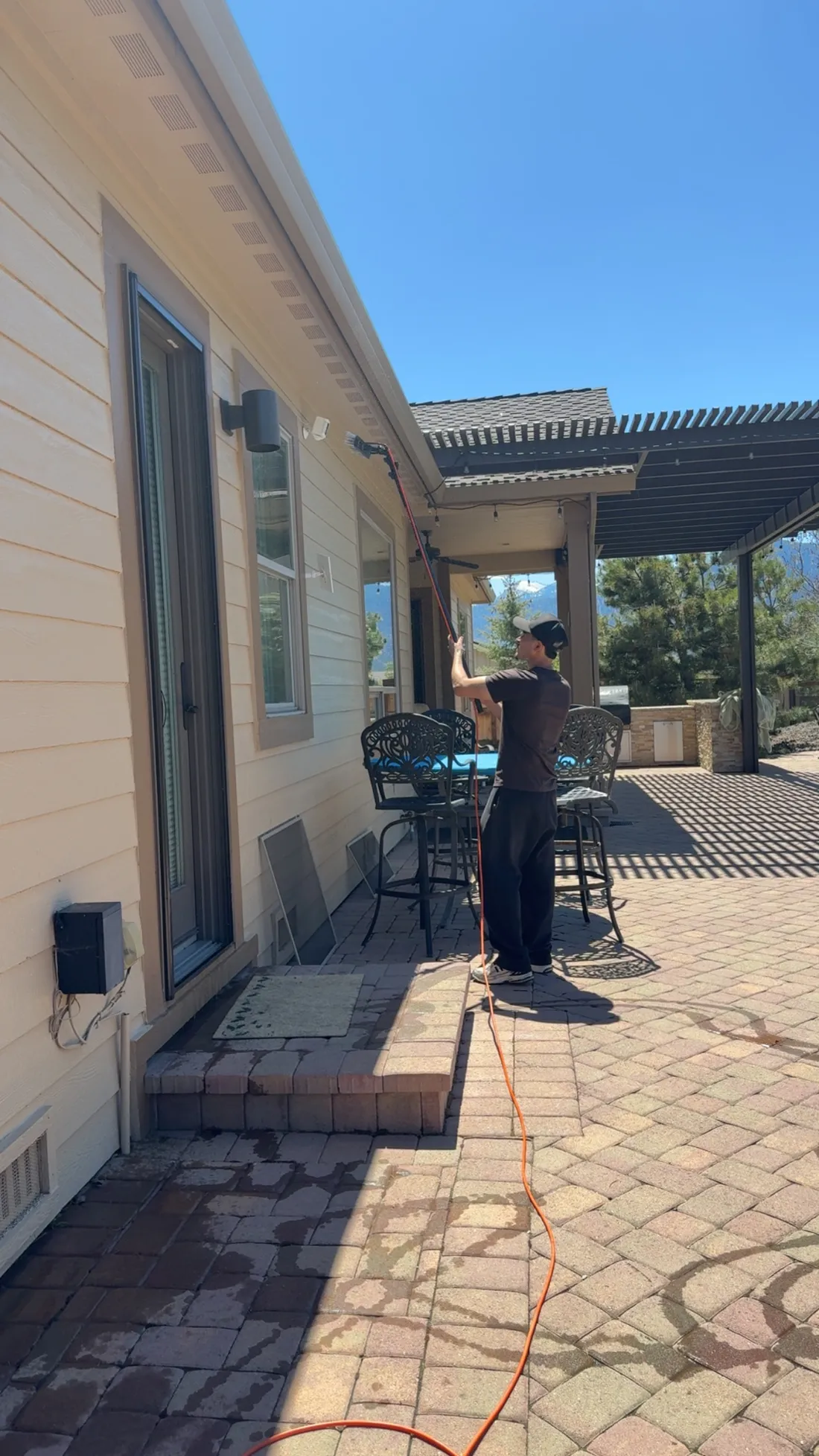 Technician cleaning residential windows on a Reno home with mountain views