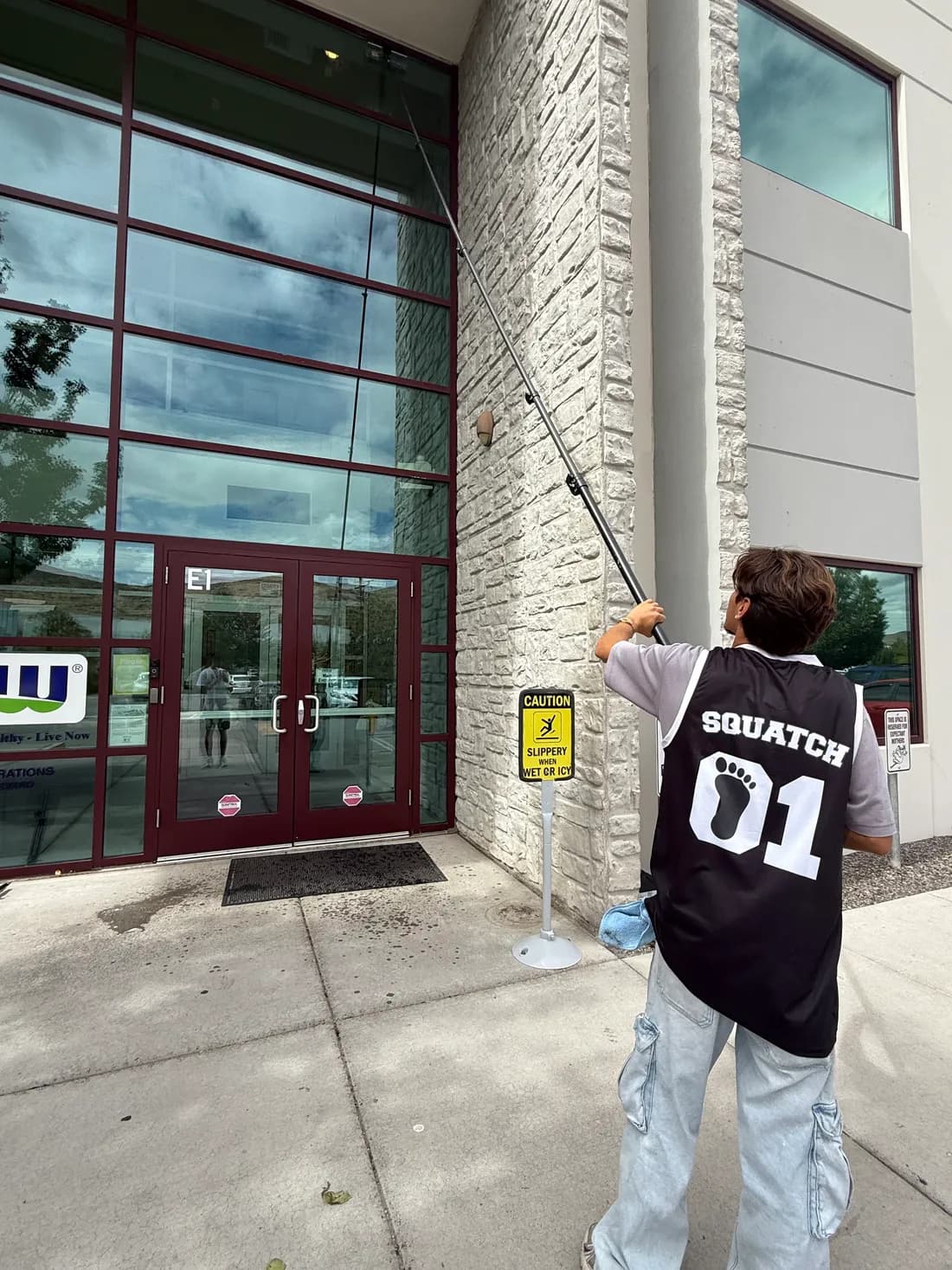 Squatch Window Cleaning team member using a water-fed pole on a storefront